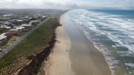 A-great-view-of-Middleton-Beach-on-the-Fleurieu-Peninsula-in-South-Australia-Split-with-Beachfront-Housing-on-one-side-and-the-beach-on-the-other-and-great-clouds-and-mist-in-the-distance