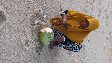 Mujer-Lombok-Local-Abriendo-Un-Coco-Para-Turistas-En-La-Playa,-Vertical