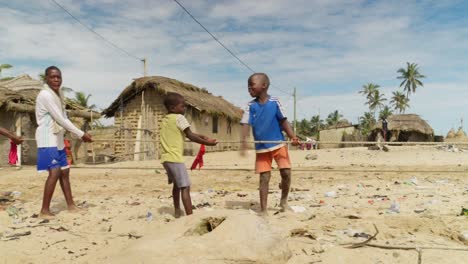 Small-boys-pull-fishing-net-by-rope-to-sand-beach-in-Moree,-Ghana