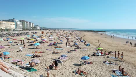 Concurrida-Playa-Praia-Do-Tarquínio-Paraíso-Con-Las-Playas-Praia-Do-Dragão-Vermelho-Y-Praia-Nova-Al-Fondo-En-Costa-Da-Caparica,-Portugal