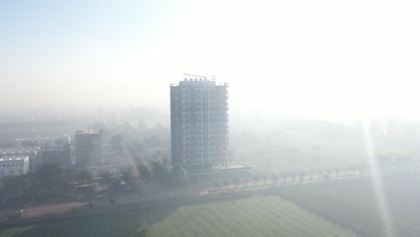 La-Toma-Aérea-De-Un-Dron-Se-Mueve-Hacia-Un-Lado-Y-Se-Ve-Un-Edificio-En-El-Medio-Y-Sus-Rayos-Caen-Sobre-Ese-Edificio.-Se-Ve-Una-Toma-Cinematográfica-De-Un-Edificio-De-Gran-Altura.