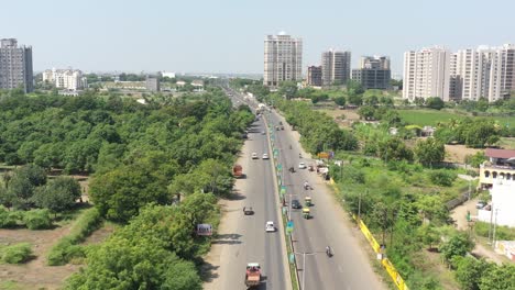 aerial-drone-shot-The-drone-camera-is-moving-around-a-road-between-dense-trees-where-many-highrise-buildings-and-lowrise-buildings-are-visible