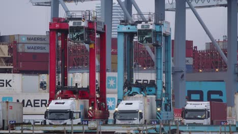 Cranes-lifting-up-shipping-containers-on-port-of-Aarhus-with-Mearsk-ship-being-loaded-in-the-background