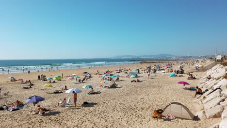 Hermosa-Y-Concurrida-Costa-De-La-Playa-De-Costa-Da-Caparica-Llena-De-Gente-En-Otoño,-Portugal