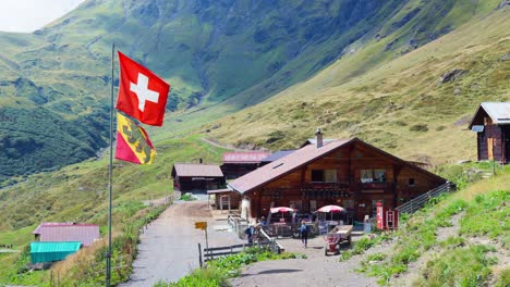 Swiss-flag-fluttering-in-the-wind-near-a-villa-in-the-Hineres-Lauterbrunnen-valley-in-Switzerland