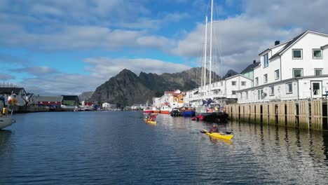 Gente-En-Kayak-A-Través-De-Henningsvaer-En-La-Isla-De-Lofoten,-Noruega,-Escandinavia---4k-Pan