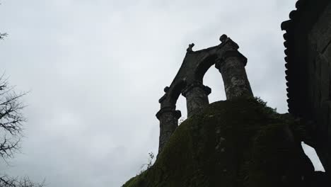 Schöne-Nach-Oben-Gerichtete-Drohnenaufnahme-Einer-Alten-Architektonischen-Struktur,-Die-Den-Eingang-Eines-Katholischen-Klosters-Mit-Einem-Christlichen-Kreuz-Oben-Zeigt,-Umgeben-Von-Großen-Bäumen-Und-Natur