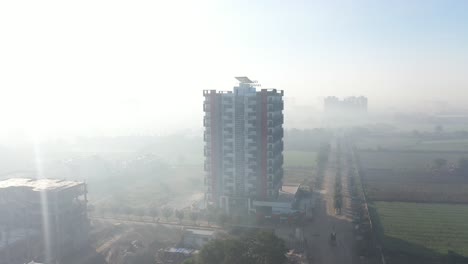 Toma-Aérea-De-Un-Dron,-La-Cámara-Del-Dron-Se-Mueve-Hacia-Un-Lado-Y-Los-Rayos-Del-Sol-Caen-Sobre-El-Edificio-Y-Se-Ven-Muchos-Campos-Grandes-Alrededor-Del-Edificio.