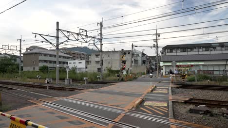 Luces-Rojas-De-Advertencia-En-El-Paso-A-Nivel-Mientras-El-Scooter-Se-Detiene-Junto-Al-Paso-A-Nivel-En-Arashiyama,-Kyoto