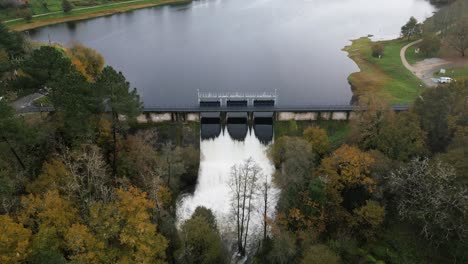 Hydraulische-Tore-Des-Cachamuiña-Stausees,-Die-An-Einem-Bewölkten-Tag,-Umgeben-Von-Bäumen-Im-Winter,-Das-Wasser-Durchlassen