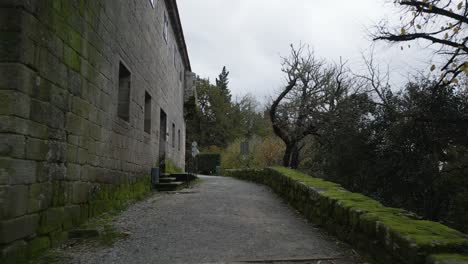 External-hallways-of-an-old-gray-brick-construction-with-slats-surrounded-by-trees-and-nature-with-windows-and-a-gray-door