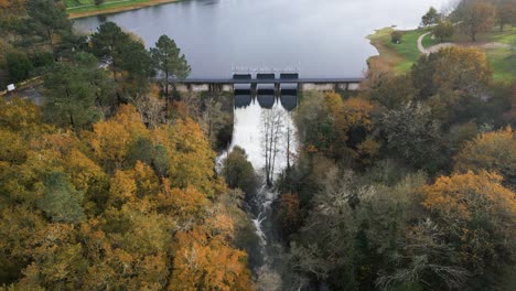 Hydraulische-Tore-Des-Cachamuiña-Stausees,-Die-An-Einem-Bewölkten-Tag,-Umgeben-Von-Bäumen-Im-Winter,-Das-Wasser-Durchlassen