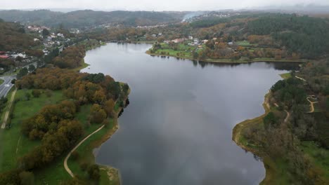 Maravillosa-Toma-Aérea-Con-Drones-Del-Paisaje-Del-Embalse-De-Cachamuiña-En-Un-Día-Nublado-Rodeado-De-Sus-Caminos,-Avenidas-Y-árboles