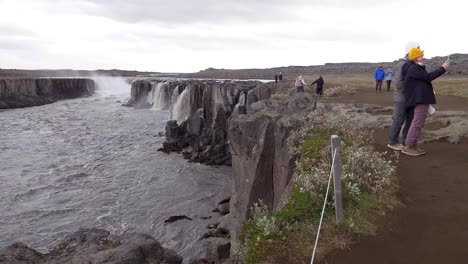 Cute-young-couple-taking-selfie-picture-at-Selfoss-waterfall-in-Iceland