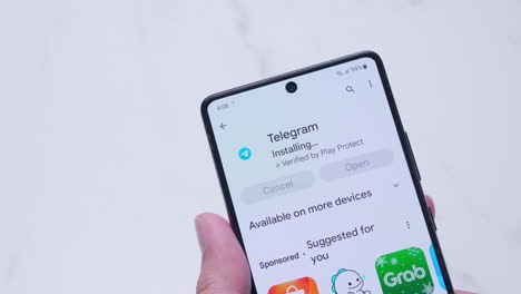 Hand-holding-a-smartphone-with-installing-Telegram-application-from-Google-play-store