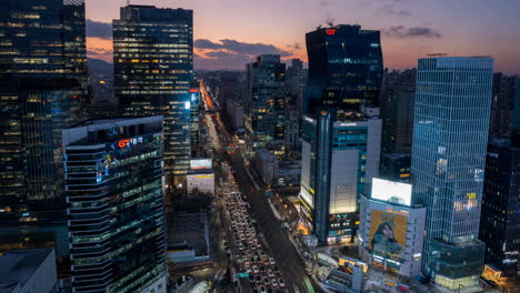 Hiperlapso-Aéreo-De-Seúl-Con-Zoom-De-Inclinación-Desde-El-Tráfico-Nocturno-De-Automóviles-De-La-Carretera-Seocho-daero-A-Los-Edificios-Corporativos-De-Oficinas-De-Gangnam-Contra-El-Pintoresco-Cielo-Del-Atardecer---Aéreo