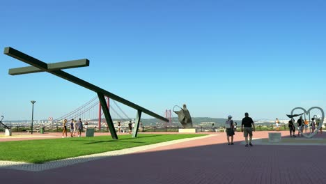 People-are-taking-selfies-at-the-Sanctuary-of-Christ-the-King-viewpoint-with-the-background-of-Lisbon-and-the-25-of-April-Bridge,-Portugal