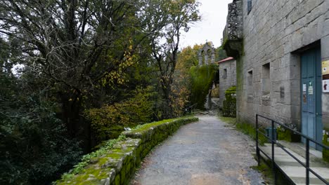 Exterior-hallway-with-a-sign-prohibiting-entry,-leads-to-the-entrances-of-a-majestic-old-construction-with-windows-and-doors-surrounded-by-trees-and-nature