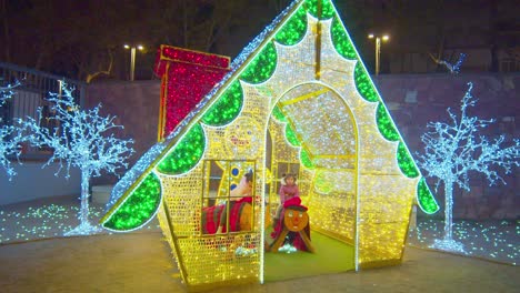 Casa-Navideña-Hecha-De-Luces-Con-Niños-Jugando-Dentro-En-Barcelona,-España