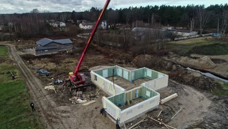 Aerial-view-of-workers-building-walls-to-a-detached-house,-cloudy-fall-day