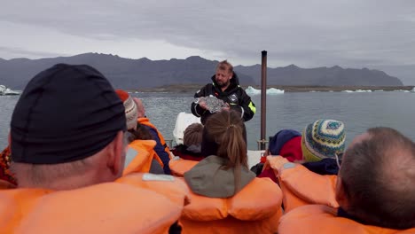 Führer-Mit-Einem-Stück-Schmelzendem-Eis-Im-Gespräch-Mit-Einer-Gruppe-Von-Touristen-Auf-Einer-Bootstour---Gletscherlagune-Jökulsárlón-In-Island