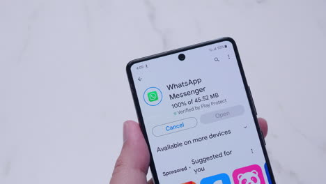 Hand-holding-a-smartphone-with-installing-Whatsapp-application-from-Google-play-store