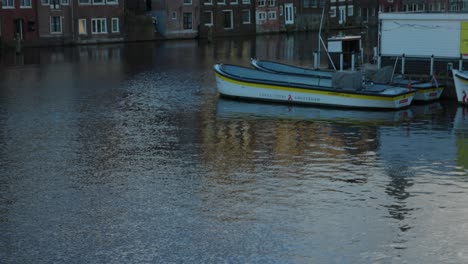 Casas-Icónicas-Del-Canal-A-Lo-Largo-Del-Damrak,-Ámsterdam-A-Primera-Hora-De-La-Mañana,-Inclinada-Hacia-Arriba