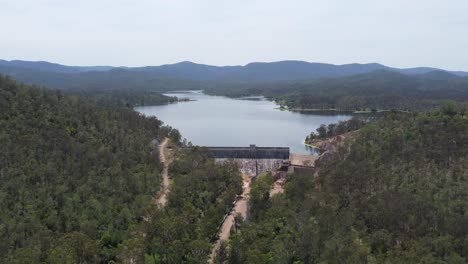 Drone-flying-towards-a-dam-and-a-dam-wall-walking-tracks-below