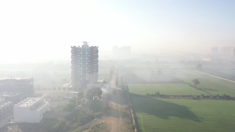 Toma-Aérea-De-Niebla-Natural-Con-Drones,-La-Cámara-Del-Drone-Avanza-Donde-Las-Casas-Residenciales-Y-Los-Grandes-Edificios-De-Gran-Altura-Están-Rodeados-De-Muchos-Campos