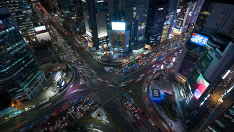 Coches-Que-Pasan-Por-La-Intersección-De-La-Estación-De-Gangnam-Por-La-Noche,-La-Calle-Más-Transitada-Del-Centro-De-Seúl-Con-Altos-Rascacielos---Vista-De-Arriba-Hacia-Abajo