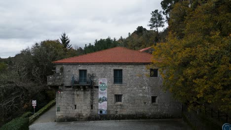 Shot-of-the-old-Saint-Peter-of-the-Rocks-monastery-with-a-red-roof,-windows,-a-long-sign-hanging-in-front-and-fences-that-prevent-passage-surrounded-by-beautiful-trees-and-nature