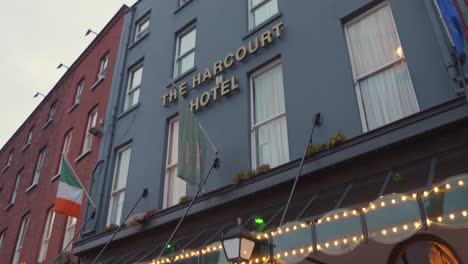 Tilt-down-shot-of-the-entrance-of-blue-colored-Harcourt-Hotel-building-in-Dublin,-Ireland-during-evening-time