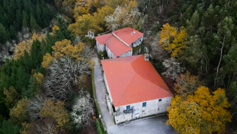 Circular-aerial-drone-shot-of-a-beautiful-old-construction-with-roll-roofs-surrounded-by-trees-and-nature