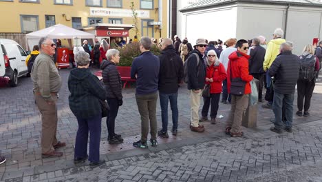 Grupo-De-Personas-Haciendo-Cola-En-El-Stand-De-Bæjarins-Beztu-Pylsur,-Una-Tradicional-Y-Famosa-Comida-Callejera-En-Reykjavik,-Islandia