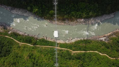 Aerial-top-down-of-jungle,-flowing-and-bridge-with-bungee-jumping-in-Nepal,-Asia