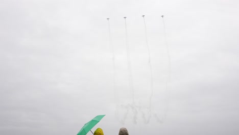 People-at-aviation-show-while-airplanes-fly-and-leave-smoke-trail-behind