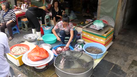 Frau-Bereitet-Rohen-Fisch-Für-Eifrige-Kunden-An-Einem-Belebten-Marktstand-Zu