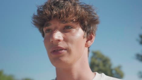 Caucasian-male-with-curly-hair-drink-energy-drink-and-smile,-sunny-summer-day