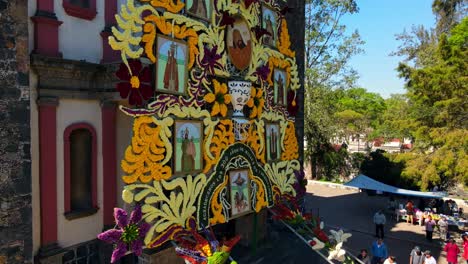 Detailed-ascent-of-a-giant-flower-arrangement-of-the-Señor-de-la-Cuevita-at-the-Iztapalapa-Cathedral,-organized-group-assembly---Drone-shot