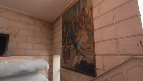 Staircase-leading-to-grand-hall-in-chateau-with-artistic-Roman-mural-in-focus