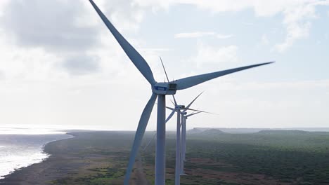 Telephoto-closeup-rear-view-of-behind-wind-turbines-spinning-in-tropical-coastal-barren-area