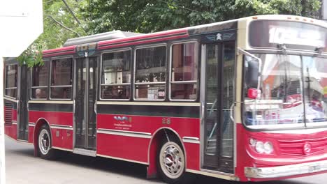 Red-Bus-Drives-in-Slow-Motion-at-Street-Intersection,-Public-Transportation