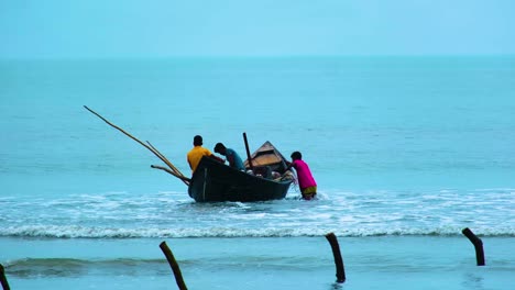 Un-Pescador-Tirando-De-Un-Barco-Pesquero-Local-Con-Pescadores-En-él,-Para-Ponerlo-En-El-Agua-Del-Mar.