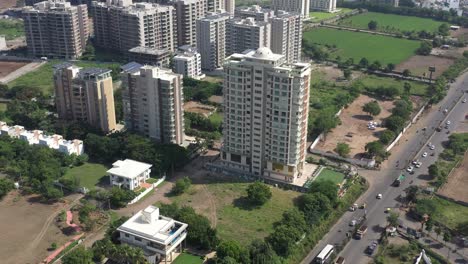 aerial-drone-shot-The-drone-camera-is-moving-upwards-where-many-high-rise-buildings-and-low-rise-buildings-are-visible-and-there-are-many-bikes,-cars,-trucks,-rickshaws-going-on-the-road