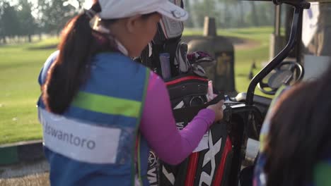 Caddy-prepares-the-golfer's-clubs-to-the-golf-cart-before-playing