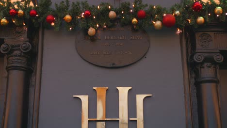 Imagen-Inclinada-Hacia-Abajo-Del-Logotipo-Del-Cartel-Frente-Al-Hotel-Harcourt-Con-Coloridas-Decoraciones-Navideñas-En-Dublín,-Irlanda