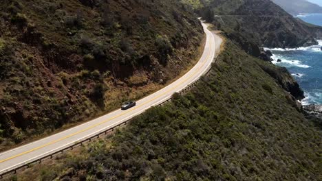 Tomas-Cinematográficas-Aéreas-De-Drones-Que-Capturan-Un-Ford-Mustang-Gris-Plateado-Mientras-Viaja-Hacia-La-Carretera-En-Medio-Del-Valle.