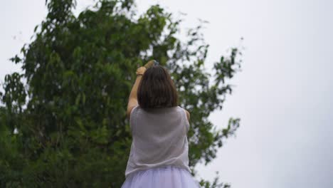 Woman-in-a-white-dress-doing-a-ritual-with-a-feather-in-her-hand-directing-it-towards-the-sky-with-smoke-and-incense,-mystical-spiritual-and-religious-energy