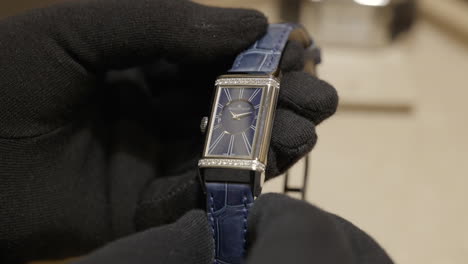 Elegante-Reloj-De-Lujo-Sostenido-Por-Una-Persona-Con-Guantes-Negros,-De-Cerca