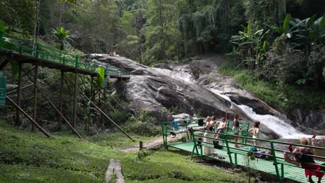 Grupo-De-Turistas-Esperando-En-Una-Plataforma-De-Metal-Verde-Esperando-Bajar-La-Cascada---Mo-Pang,-Tailandia